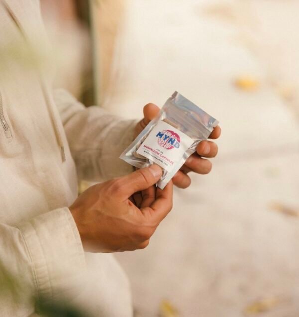 Mynd mushroom capsules in a packet held by a young man's hands