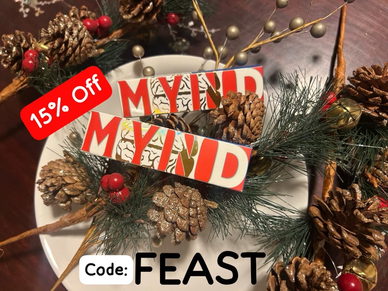 Two Christmas color themed mynd chocolate bars on a white plate with chocolate cones on the side. Holiday decorations and a 15% off coupon code. Mynd mushroom chocolate